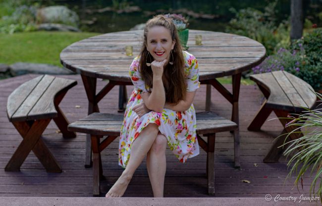 Woman in white floral dress sitting at a picnic table